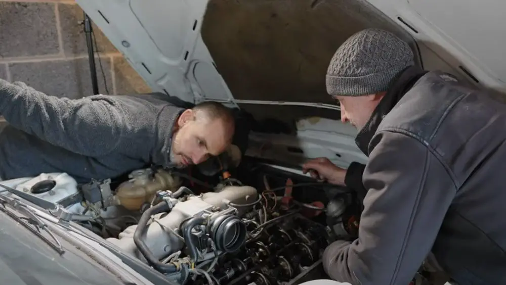 Jonny Smith (left) and Tony work on the engine of a 1983 BMW E12 Sedan 