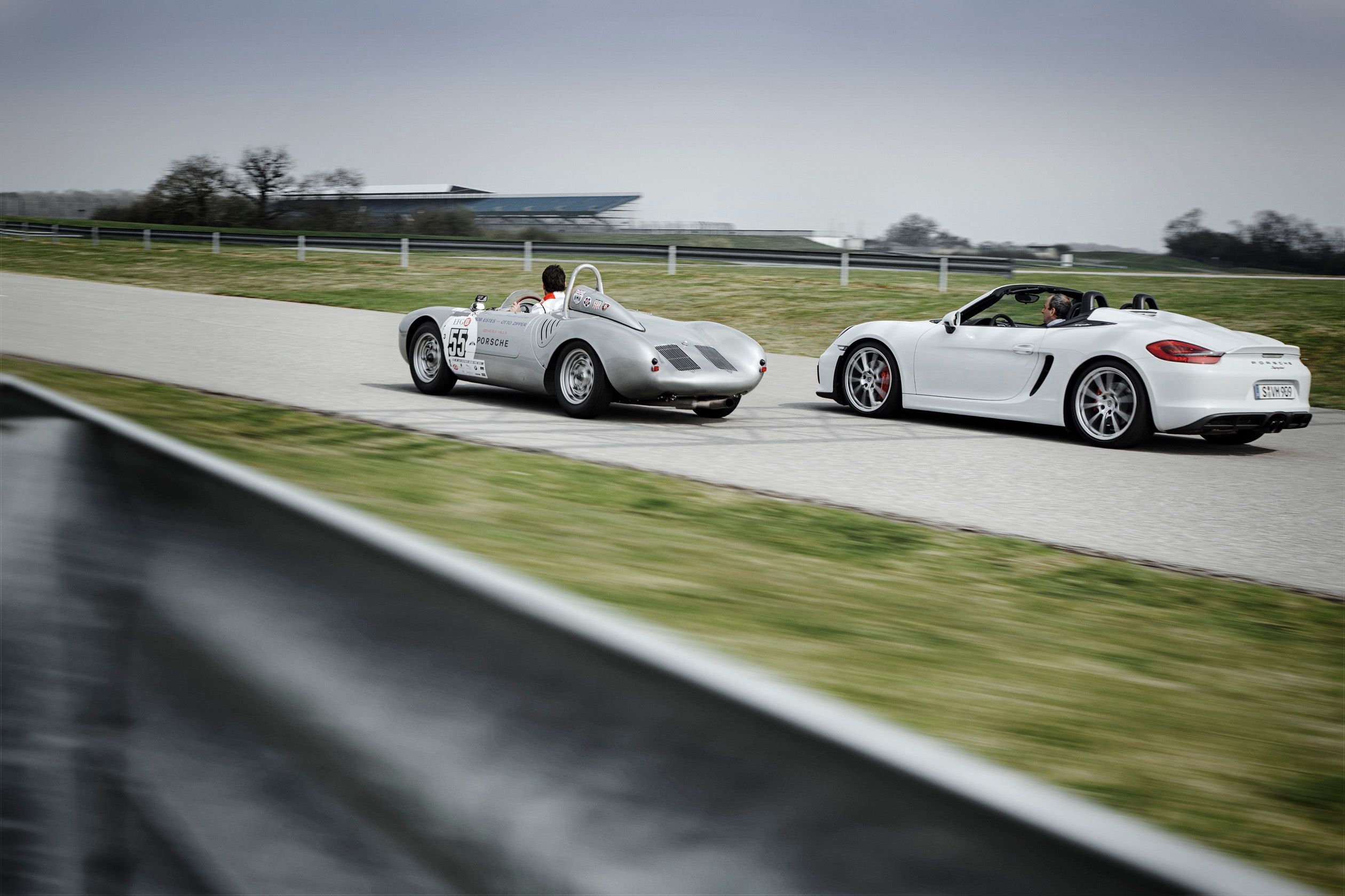 Porsche 550 on the track racing with another car.